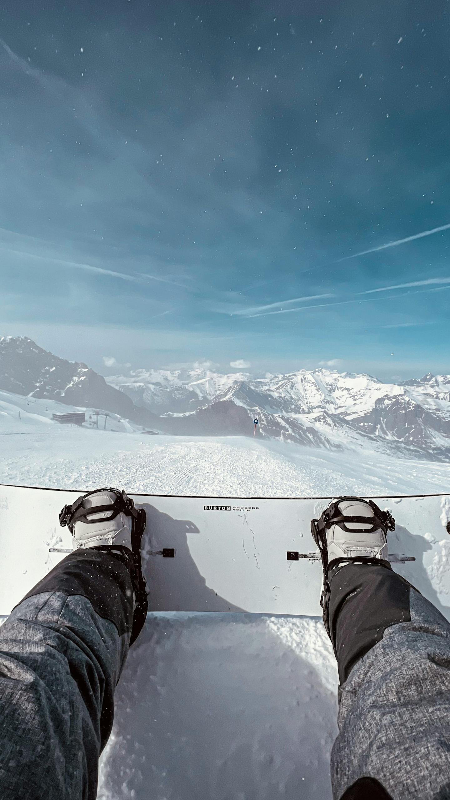 Snowboarder's feet on a snowy slope with stunning Alpine mountain panorama.